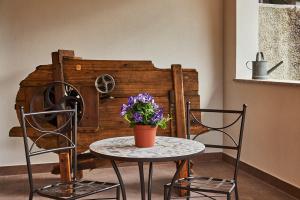 a table with two chairs and a vase with purple flowers at Agriturismo La Corte di Muggiano in Baggio +5 photos
