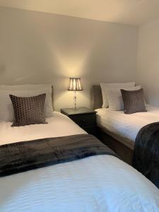 two beds in a room with a lamp on a table at The Granary, Upper Largo in Kirkton of Largo
