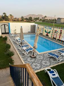 a swimming pool with lounge chairs and umbrellas at Lemon Tree apartments luxor in Al Aqālitah