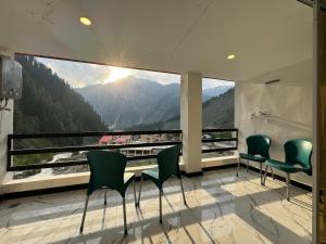 a room with chairs and a view of a mountain at Belmont Naran in Naran