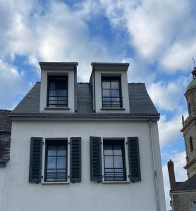 a white house with three windows and a clock tower at Plein centre Auray - Grand duplex 2 chambres avec terrasse ensoleillée in Auray