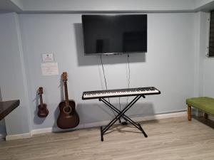 a keyboard and a tv on a wall with two guitars at Honu Waikiki by ALOH in Honolulu