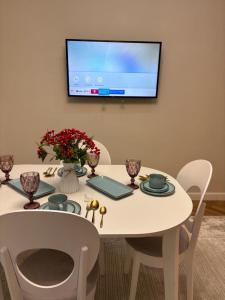 a white table with chairs and a tv on a wall at Новый ЖК Capital City, элитная квартира in Shymkent