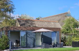 a glass house with an umbrella in front of it at Tiny House 14 in Ureterp