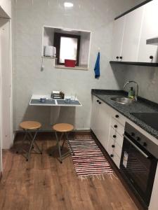 a kitchen with a sink and a counter with two stools at -Precioso apartamento en pleno corazón de A Guarda in A Guarda