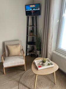 a living room with a table and a chair and a tv at La P'tite Maison D'Auron in Bourges
