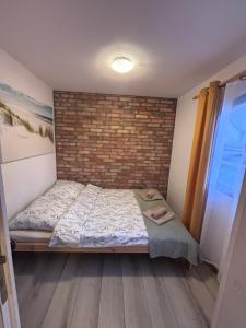 Un dormitorio con una cama y una pared de ladrillo. en Siedlisko PoMaLeńku, en Żarnowska