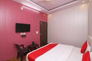 ファリーダーバードにあるOYO 81074 Hotel Adbのベッドと薄型テレビのある寝室