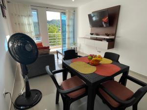 a room with a table with a fan and a television at Apartamento con Piscina y Vista panoramica Anapoima Centro in Anapoima