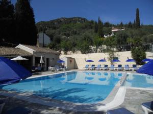 una gran piscina con sombrillas y sillas azules en Elli Marina Studios and Apartments, en Benitses