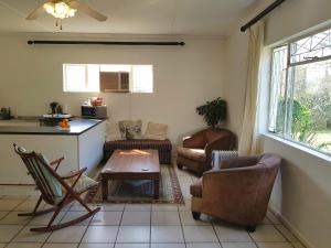 a living room with chairs and a table and a kitchen at Cottage with Farmyard Garden on the Sunshine Coast in Alexandria