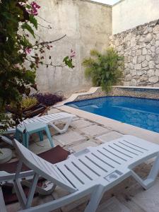 a white lounge chair next to a swimming pool at Purple Lotus Cozumel in Cozumel