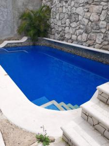a blue swimming pool next to a stone wall at Purple Lotus Cozumel in Cozumel