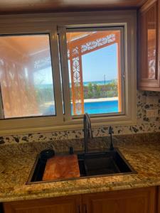 a kitchen counter with a sink and two windows at Amoun sea view in Qaryat Shurūq +28 photos