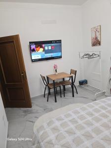 a room with a table and a tv on the wall at Casa Amy in Acqui Terme