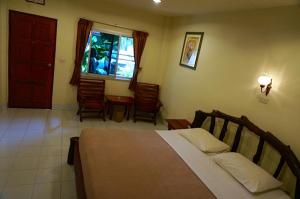 a bedroom with a bed and a table and a window at Market motel Aranyaprathet in Aranyaprathet