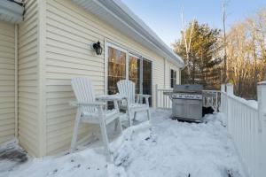 a patio with two chairs and a table in the snow at Winnisquam Landing Lakefront Firepit Deck in Tilton