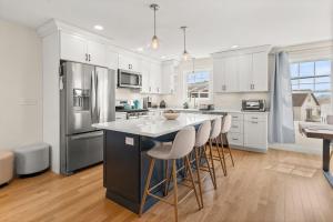 a kitchen with white cabinets and a island with bar stools at Sunset Views Balcony Marsh Views AC in Hampton