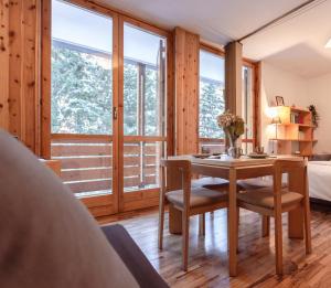 una camera da letto con tavolo, sedie e un letto di [* * *Premium Loft* * *] vista Marmolada ad Alba di Canazei