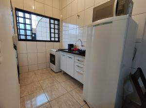 eine Küche mit einem weißen Kühlschrank und einer Spüle in der Unterkunft Apto Completo - Ar Condicionado e Garagem 01 in Barretos