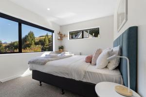 a bedroom with a large bed and a large window at Lake View Viscount in Queenstown