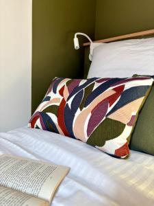 ein Buch auf einem Bett mit einer bunten Decke darauf in der Unterkunft Home Chic Home - Le Cocon de Paris La Défense in La Garenne-Colombes + 34 Fotos