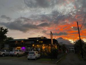 a building with cars parked in front of it with a sunset at Hotel Arenal Rabfer in Fortuna