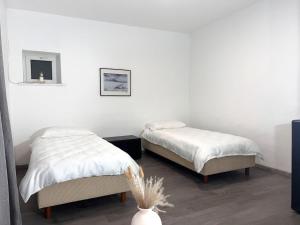 two beds in a room with white walls at Modern classic apartment in Lauenau