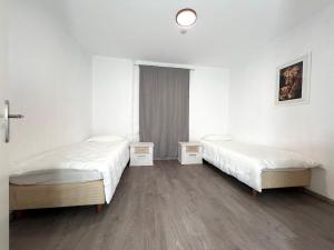 two beds in a room with white walls and wooden floors at Modern classic apartment in Lauenau