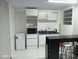 a white kitchen with a refrigerator and a microwave at Lo de Po-Ly in Chuy