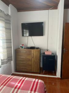 ein Schlafzimmer mit einem TV und einer Kommode mit einem Bett in der Unterkunft Casa de Hospedagem Ave Maria 2 in Cachoeira Paulista