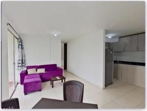 Serenity Inn Jamundi في Jamundí: غرفة معيشة مع أريكة أرجوانية ومطبخ