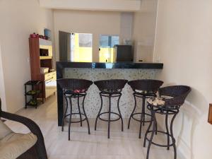 a bar with four stools in front of a kitchen at Aconchego da Zuca in Barra Grande +9 photos