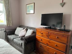 a living room with a couch and a television on a dresser at Brada View Bamburgh in Bamburgh