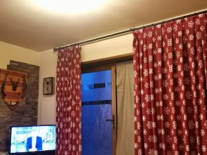 a room with a window with curtains and a television at Casa de piedra y madera vistas a montañas y prados in Bellver de Cerdanya 