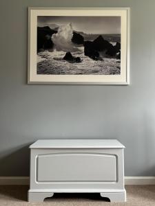 a picture hanging on a wall above a white dresser at Brada View Bamburgh in Bamburgh