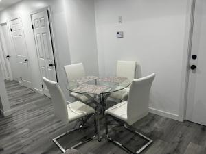 a dining room with a glass table and white chairs at Basement in Keswick Edmonton in Edmonton +1 photo