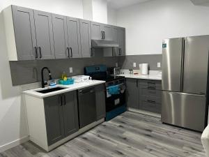 a kitchen with gray cabinets and a stainless steel refrigerator at Basement in Keswick Edmonton in Edmonton