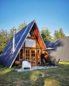 a large wooden house with a large window and a white chair at Cabaña Alpina Los Treiles in Panguipulli