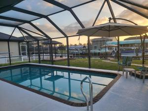 a swimming pool with an umbrella and chairs and a table at Pelican Coast in Fort Myers