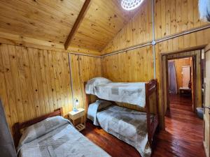 a room with three beds in a wooden cabin at Rincon Soñado in Villa Yacanto