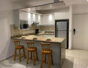 eine Küche mit einer Theke mit drei Barhockern in der Unterkunft Tonsupa, Suite Grand Diamond Beach in Tonsupa + 3 Fotos