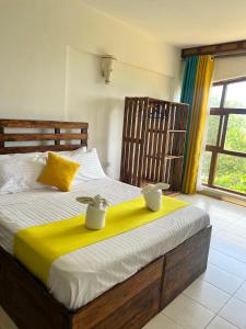 a bedroom with a large bed with yellow and white sheets at Golden Beachfront Studios Diani in Diani Beach +38 photos