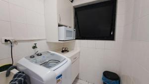 a small bathroom with a sink and a microwave at Pitangueiras Pé na Areia in Guarujá