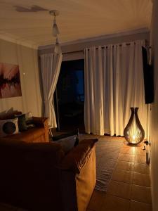 a living room with a couch and a vase on the floor at Pitangueiras Pé na Areia in Guarujá