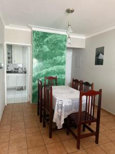 a dining room with a table and a green wall at Pitangueiras Pé na Areia in Guarujá