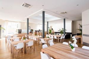 a restaurant with wooden tables and white chairs at Hôtel Atrium in Lourdes