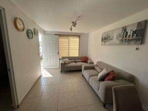 克雷塔罗Casa Privada El Marqués Qro的客厅里有两张沙发,墙上挂着一个钟