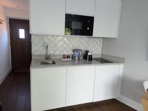 a kitchen with white cabinets and a counter top at Ox Lane Annexe - Harpenden in Harpenden +3 photos