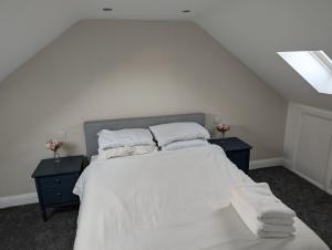a bedroom with a large white bed with two night stands at Ox Lane Annexe - Harpenden in Harpenden